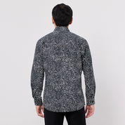 Person wearing a black and white patterned shirt on a plain background