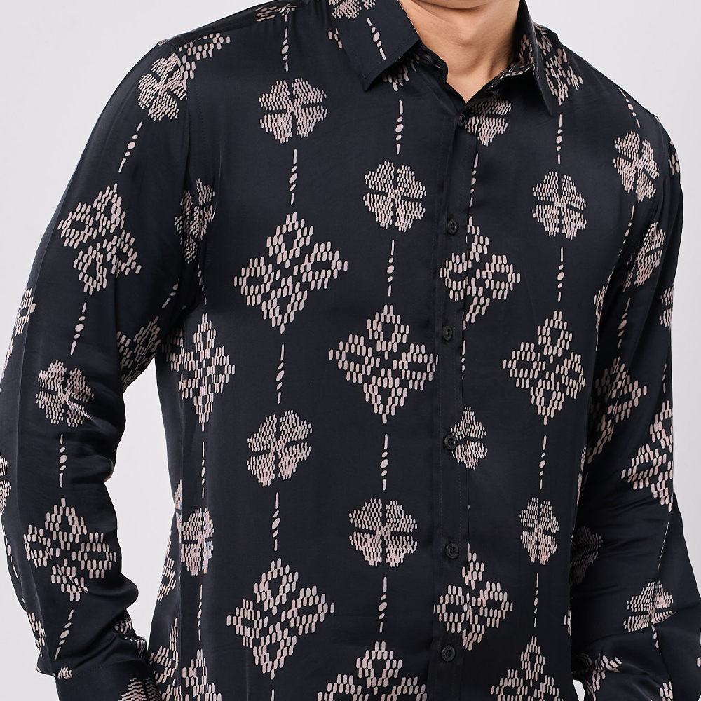 Black shirt with geometric pattern worn by a person on a gray background