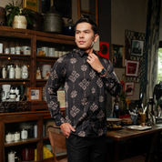 Man adjusting his shirt in a room with shelves and decor