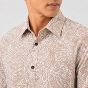 Man wearing a beige patterned shirt with a plain background