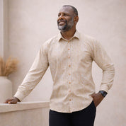 Man wearing a beige patterned shirt against a neutral background