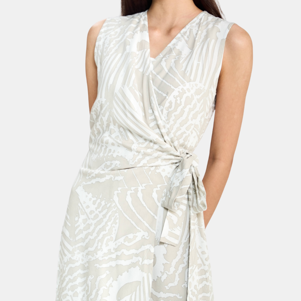 A sleeveless wrap-style dress with a V-neckline and self-tie waist, featuring an abstract white and light beige pattern, shown on a model against a light gray background.