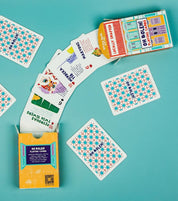 Playing cards with geometric designs and colorful packaging on a teal background