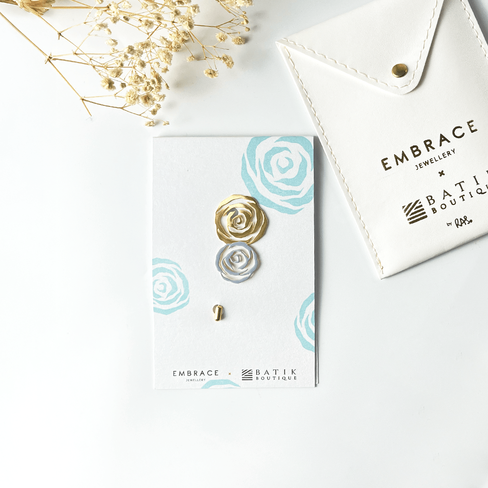 Jewelry set with gold and silver rose-shaped earrings on a branded card, with 'Embrace Jewellery' and 'Batik Boutique' branding.