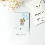 Jewelry set with gold and silver rose-shaped earrings on a branded card, with 'Embrace Jewellery' and 'Batik Boutique' branding.