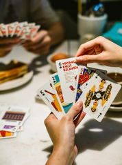 Person holding playing cards with colorful designs on a table.
