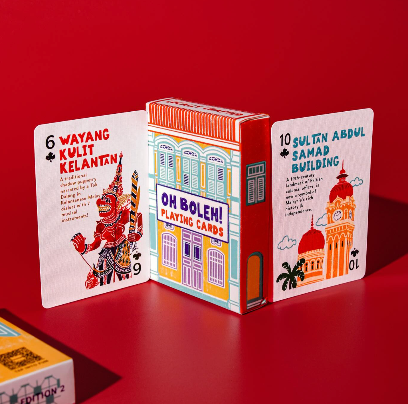 Playing card set with colorful box featuring architectural designs on a red background