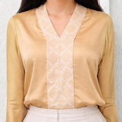 Beige blouse with white geometric pattern on a plain background
