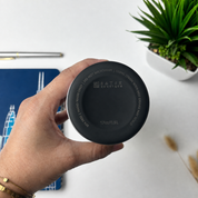 A hand holds a black round container lid with white text that reads 'BATIK BOUTIQUE' and '17oz/0.5L'.
