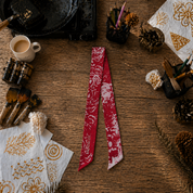 Red and white patterned scarf on a wooden surface with decorative items.