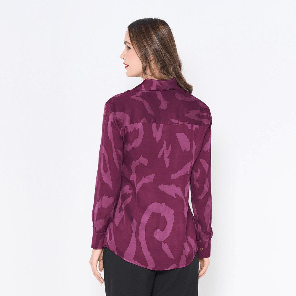 a woman showcasing the back of batik shirt in the pattern plum rimba against a white background