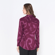 a woman showcasing the back of batik shirt in the pattern plum rimba against a white background