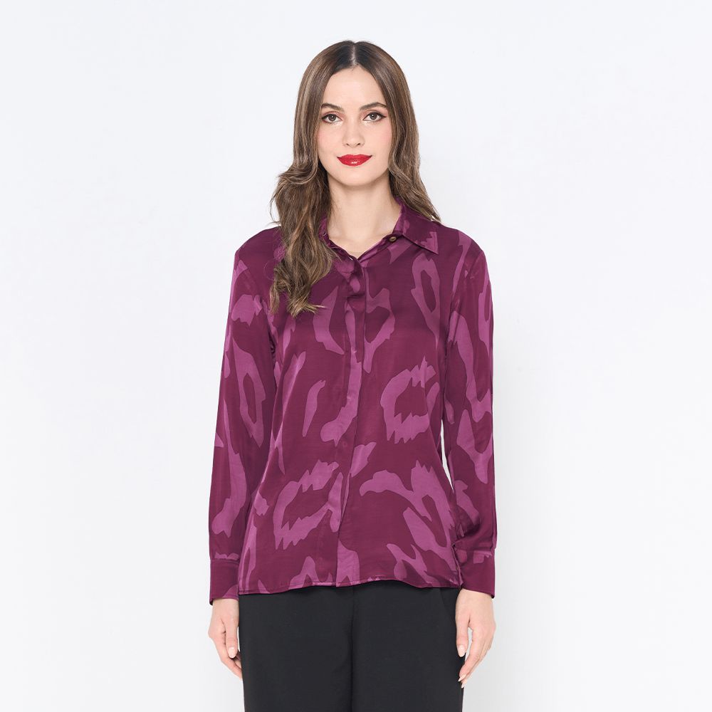 a woman posing in a batik shirt in the pattern plum rimba against a white background