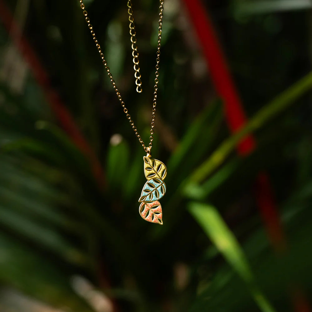 Necklace with leaf-shaped pendants hanging against a blurred green background