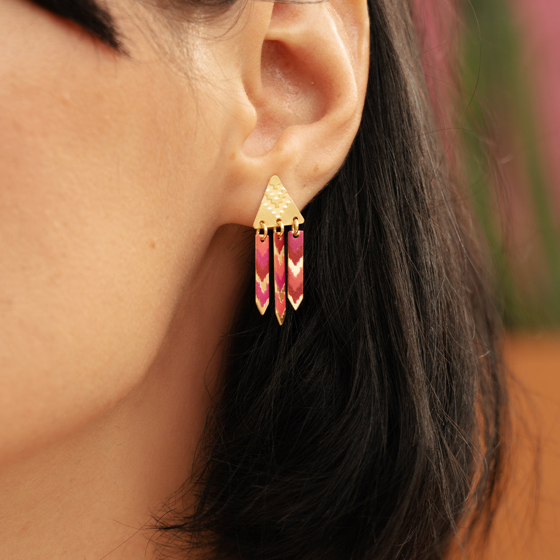Close-up of a person wearing gold earrings with pink stones.
