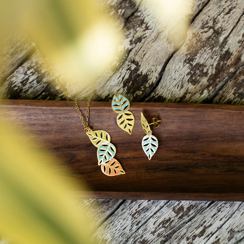 Leaf-shaped jewelry set on a wooden surface with natural light