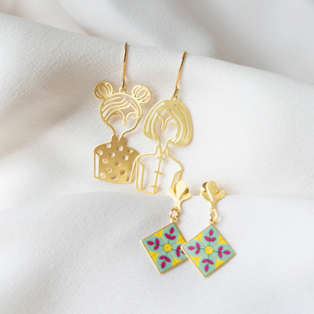 Gold earrings with floral designs on a white fabric background
