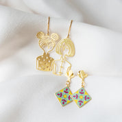 Gold earrings with floral designs on a white fabric background