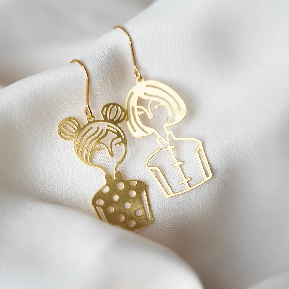 Gold earrings on a white fabric background