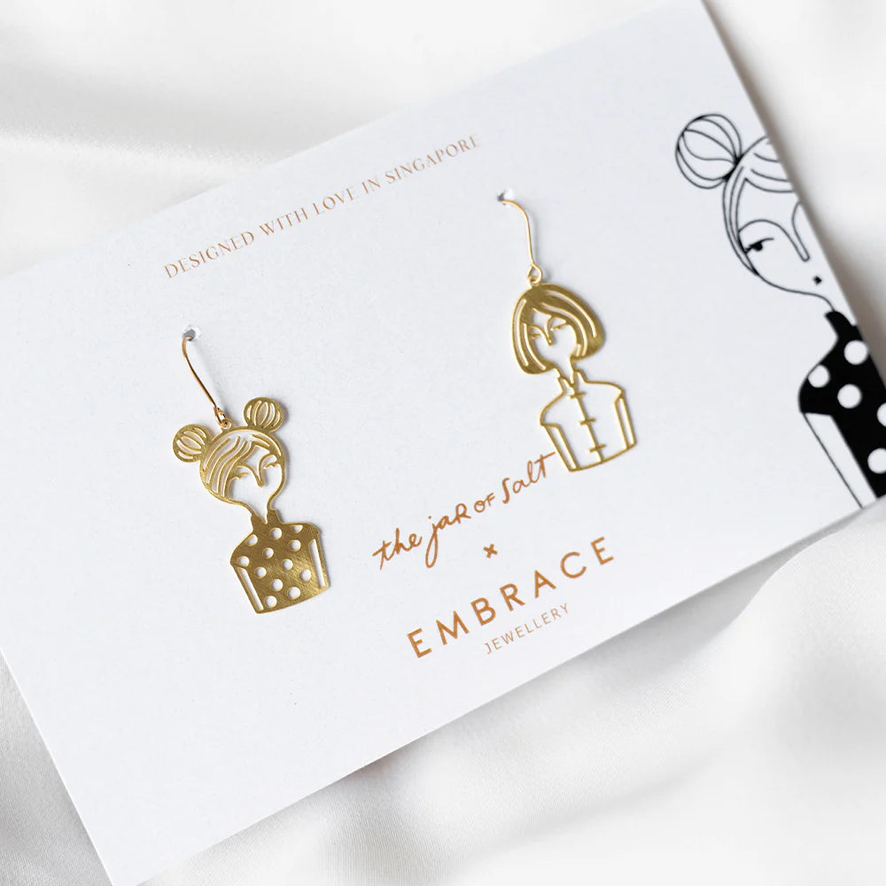Gold earrings on a branded card with 'Embrace Jewellery' and 'The Job or Salt' branding.