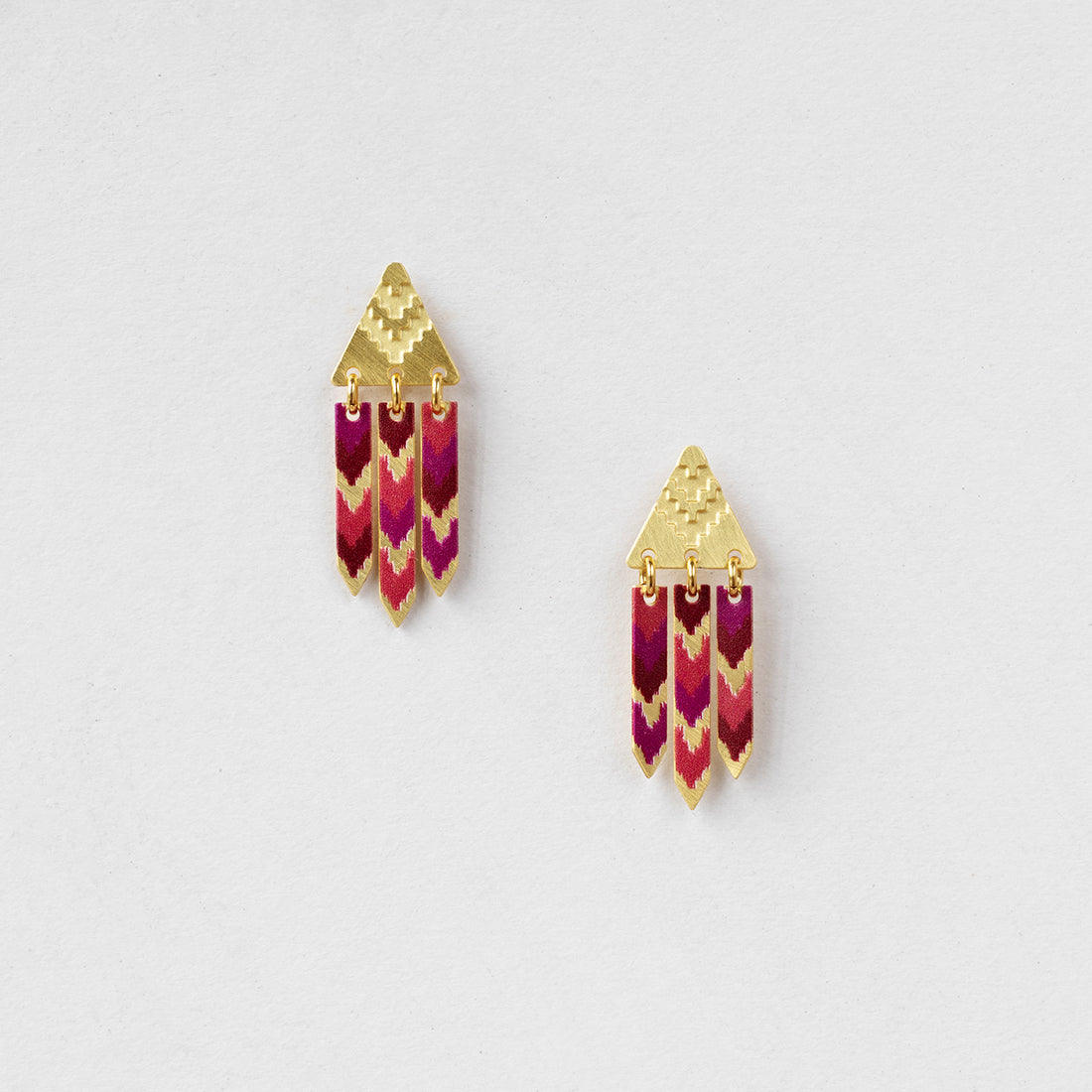 Pair of earrings with gold and pink design on a light gray background
