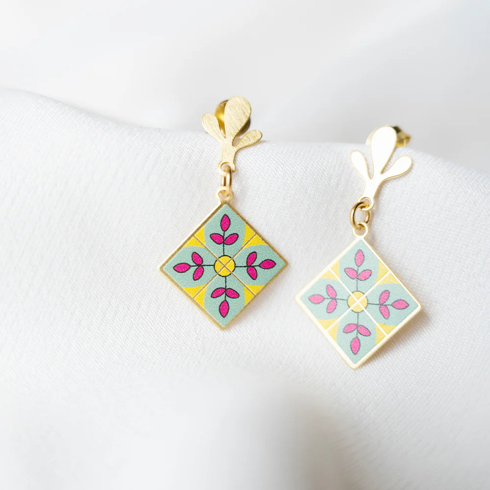 Pair of square-shaped earrings with floral design on a white background