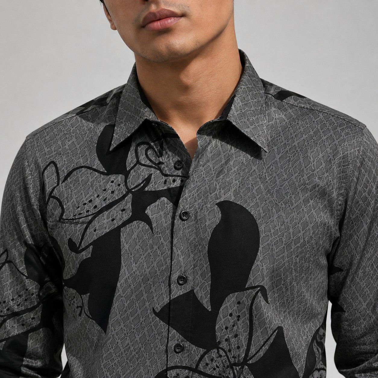 Man wearing a gray patterned shirt with black designs on a plain background