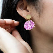 Close-up of a person wearing a 
briana floral earring with gold accents.