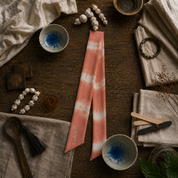 Tie-dye pink and white bandana on a wooden surface with various items.